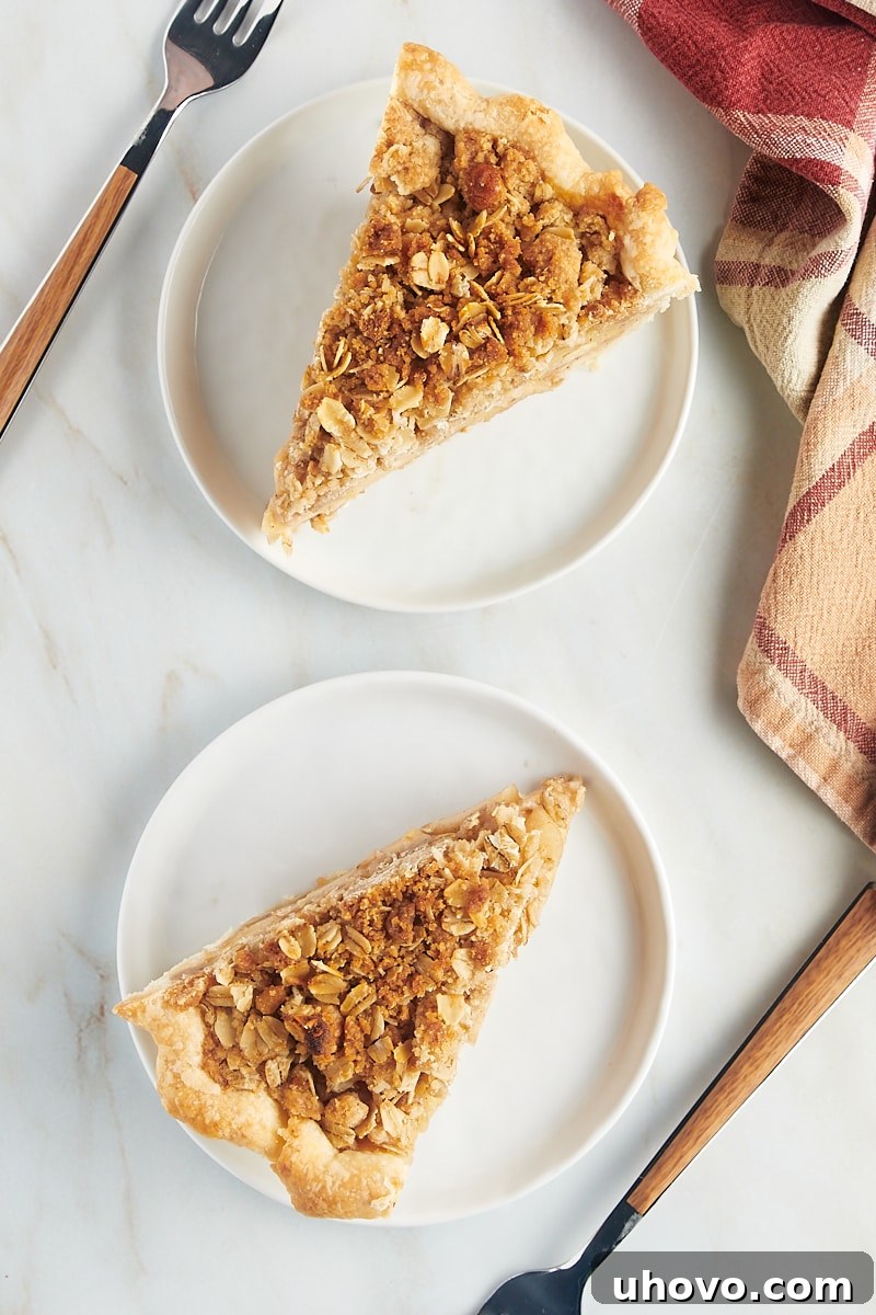 An overhead shot showcasing two perfect slices of apple crumb pie, each on its own white plate, highlighting the golden crumble, tender apples, and flaky crust.