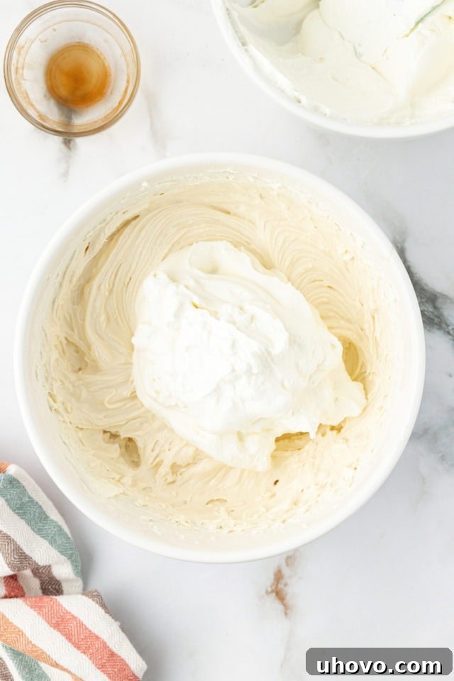 Overhead view of delicate whipped cream being added to the cream cheese mixture