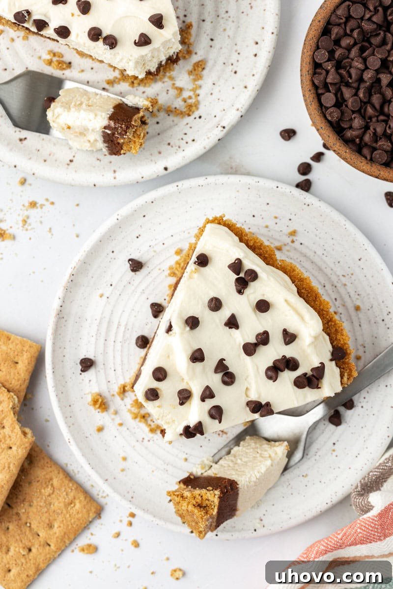 Overhead view of a slice of chocolate cookie dough cheesecake on a plate with the tip of the cake on a fork, ready to be enjoyed