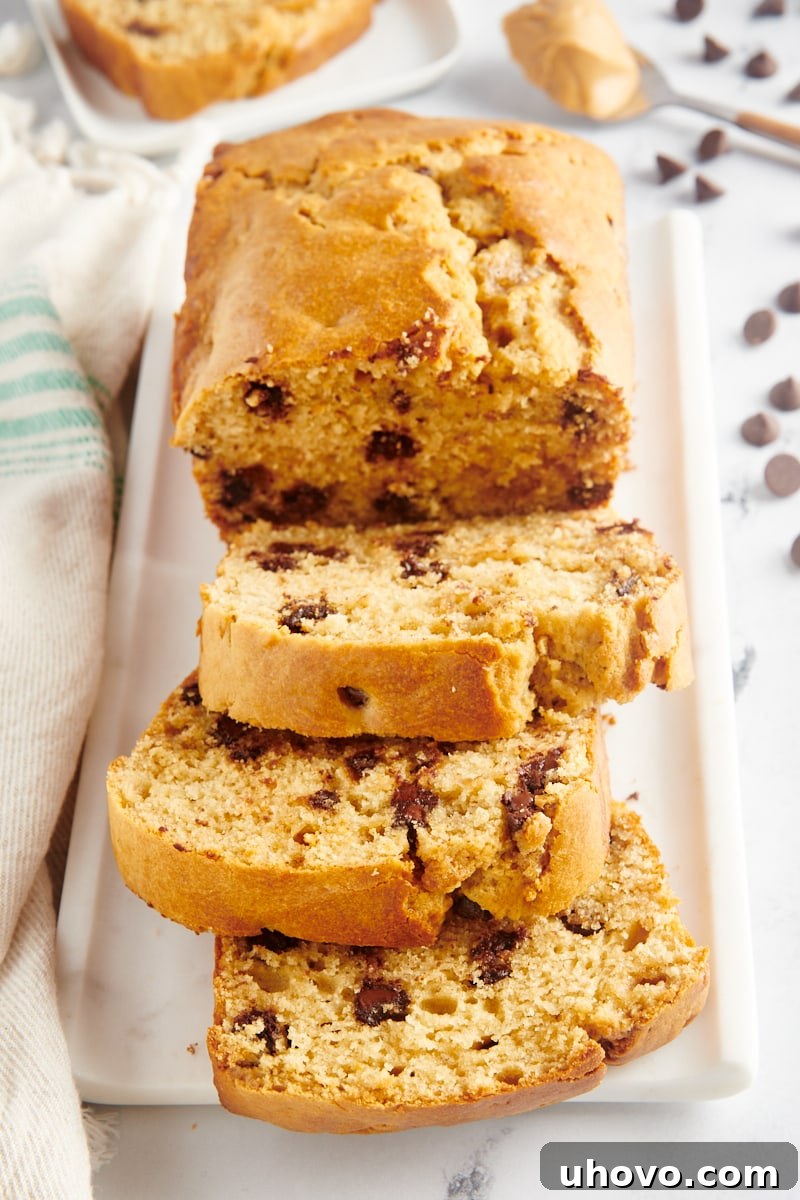 Sliced Chocolate Chip Peanut Butter Bread on a platter with three pieces cut, showcasing its moist texture and abundant chocolate chips.