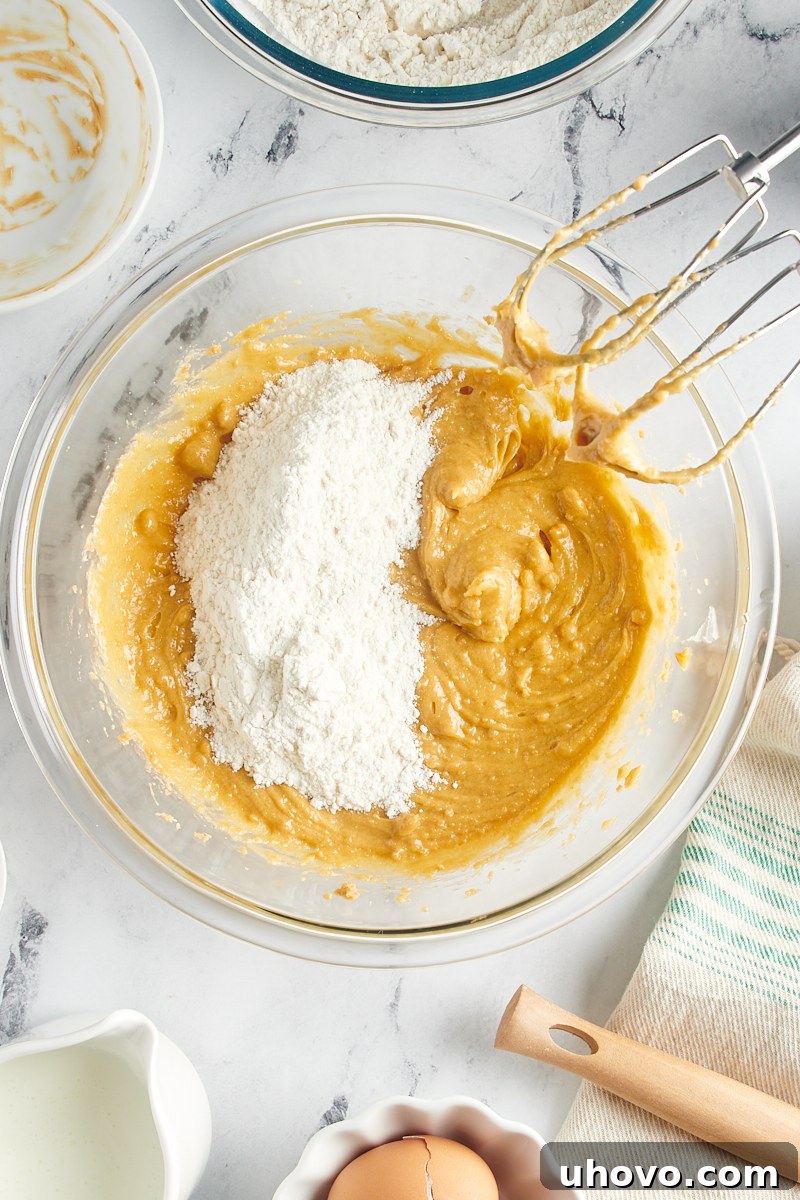 Overhead view of a portion of the dry ingredients being added to the wet batter in a mixing bowl.