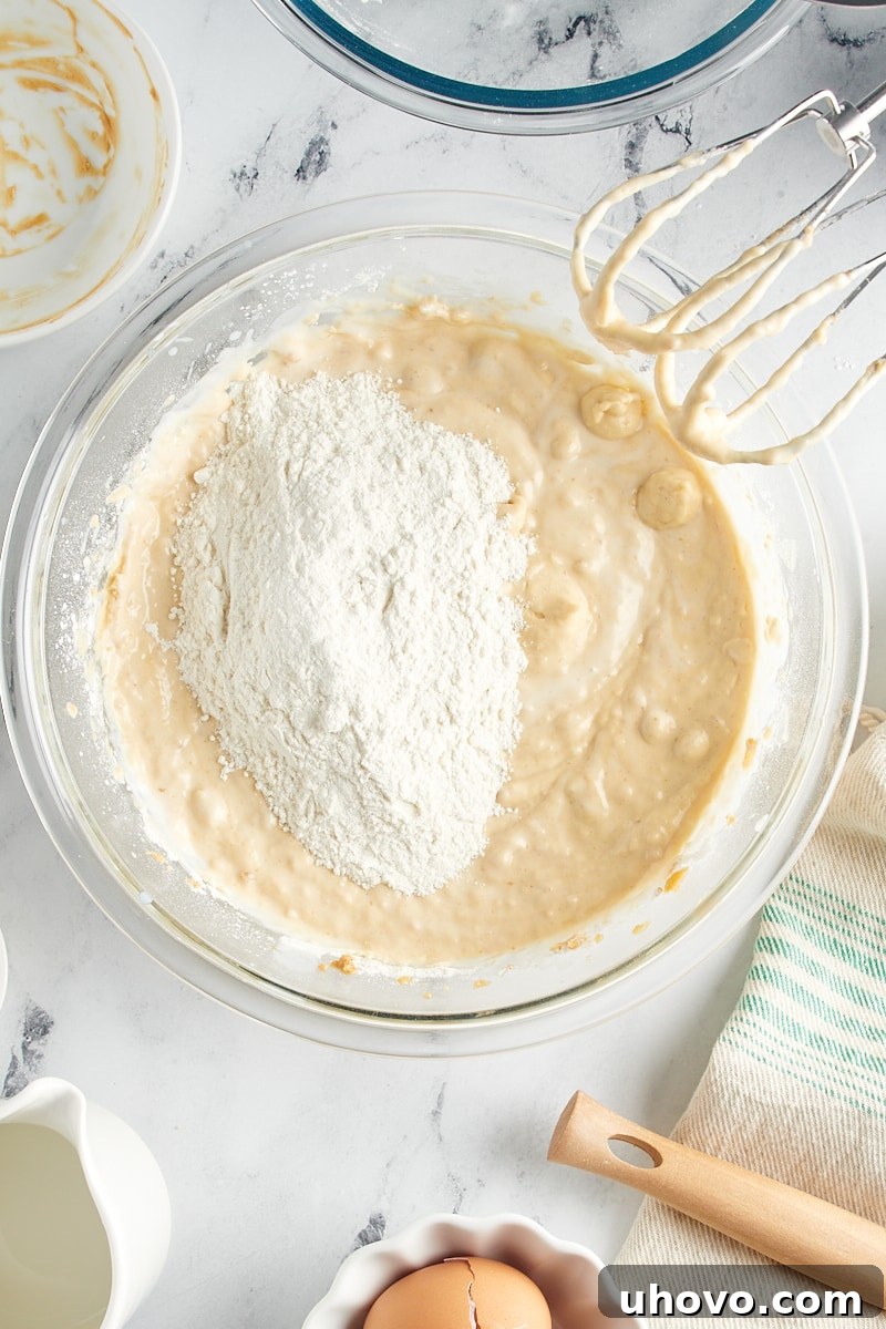 Overhead view of the final portion of dry ingredients added to the wet ingredients in a mixing bowl, prior to final mixing.
