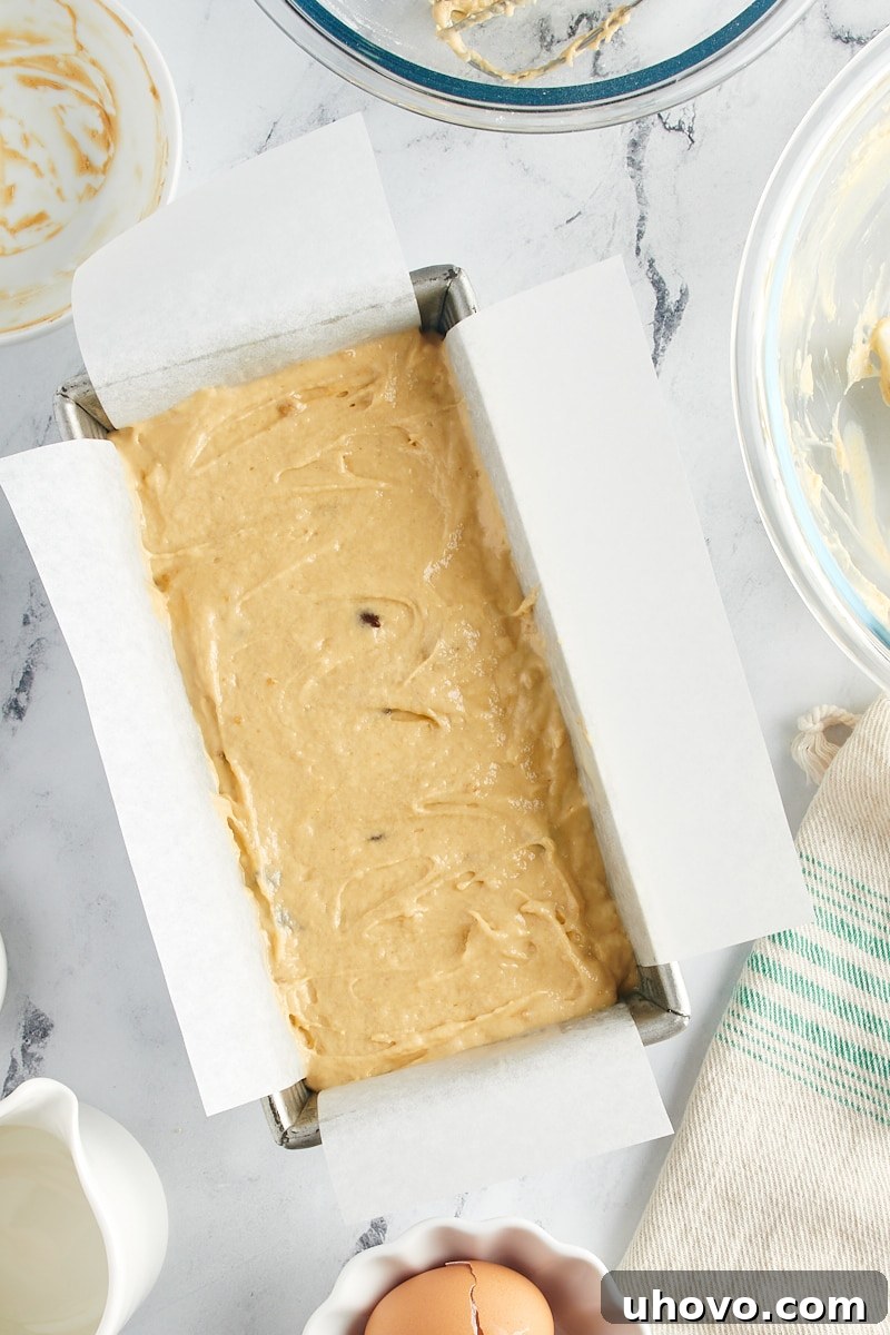 Overhead view of the chocolate chip peanut butter bread batter neatly poured into the prepared loaf pan, ready for baking.