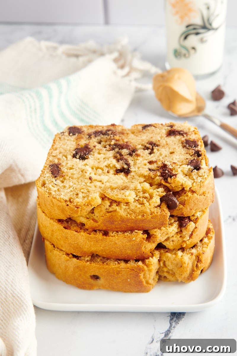 A stack of three generous slices of Chocolate Chip Peanut Butter Bread, perfectly baked, on a white square plate.