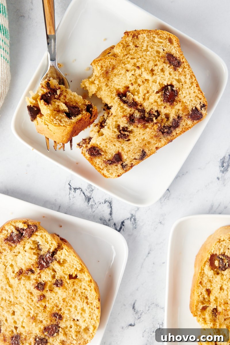 Four perfectly sliced pieces of Chocolate Chip Peanut Butter Bread served on individual white square plates.
