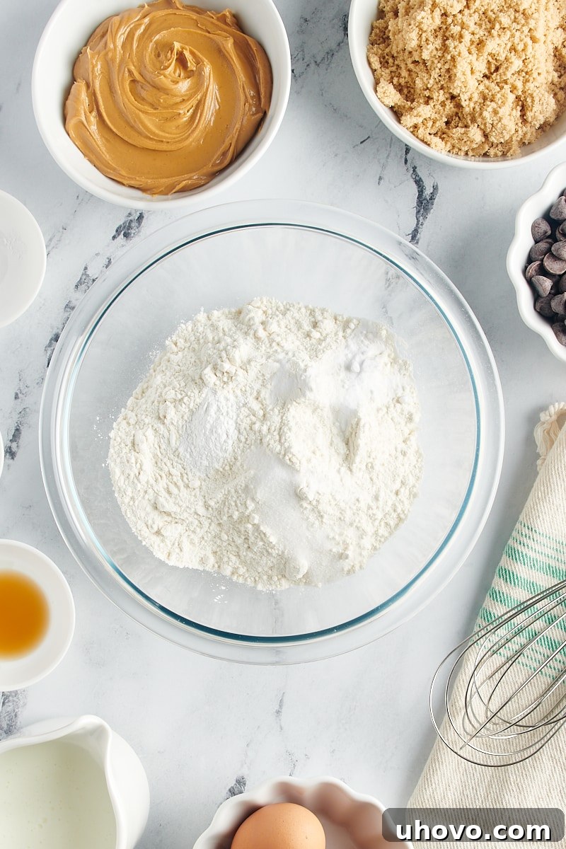 Overhead view of dry ingredients (flour, baking powder, baking soda, salt) in a mixing bowl before being whisked.