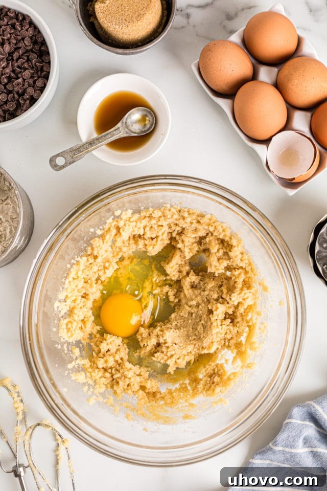 Overhead view of egg added to wet ingredients in mixing bowl