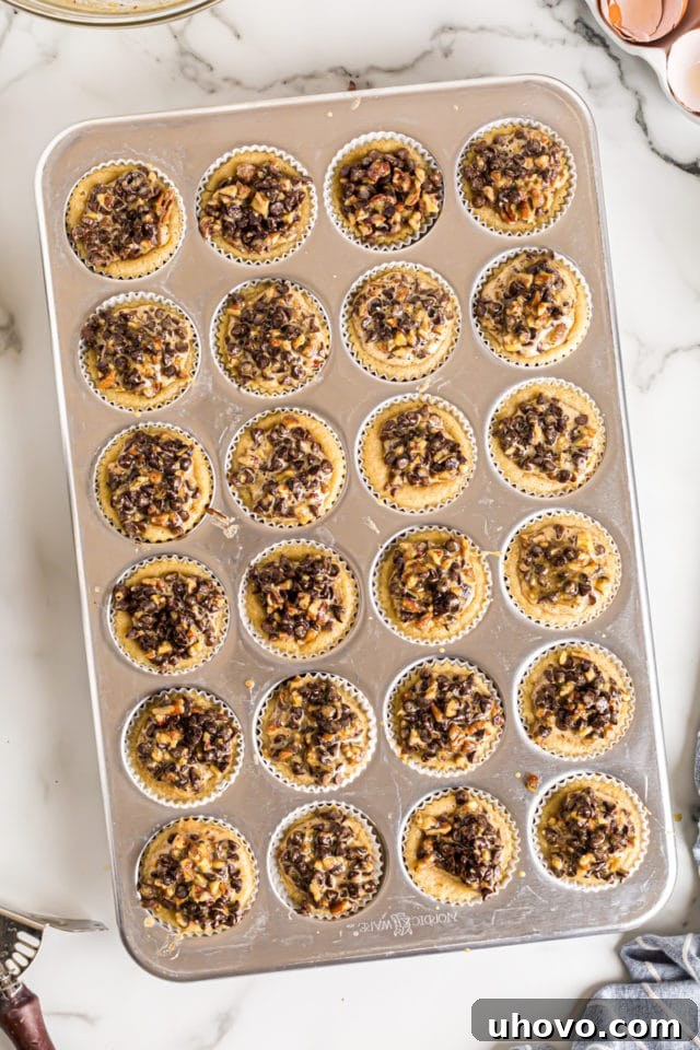 Overhead view of chocolate chip cupcakes in muffin tin after adding topping