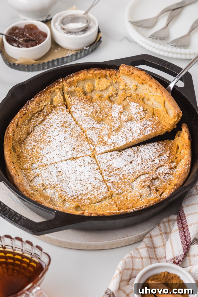 a Dutch baby pancake topped with powdered sugar in a cast iron skillet, ready to be served
