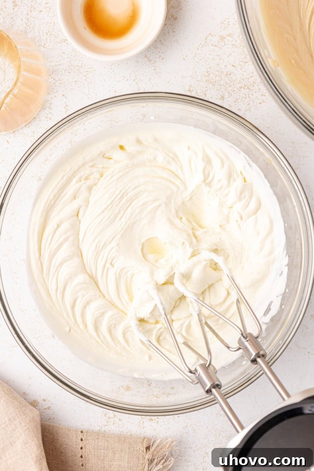 Freshly whipped heavy cream in a clear glass mixing bowl, showing light and airy soft peaks.