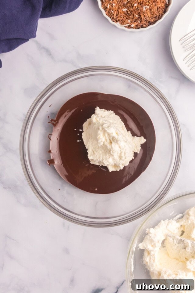 Overhead view of gently folded whipped cream being incorporated into a smooth chocolate mixture for the mousse.