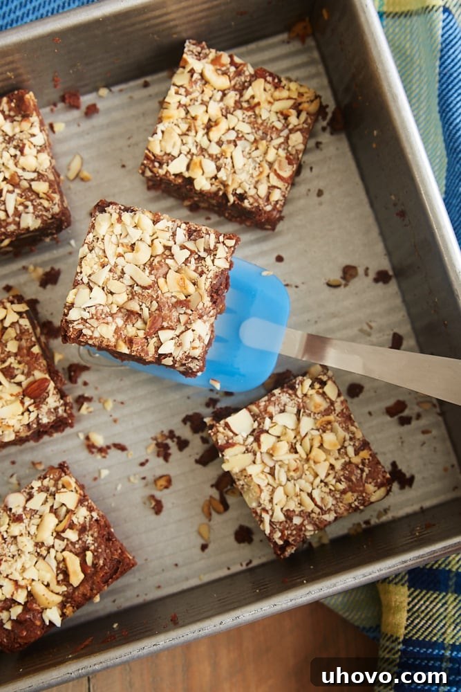 Freshly baked Extra Nutty Brownies cooling in a square baking pan, ready to be sliced.