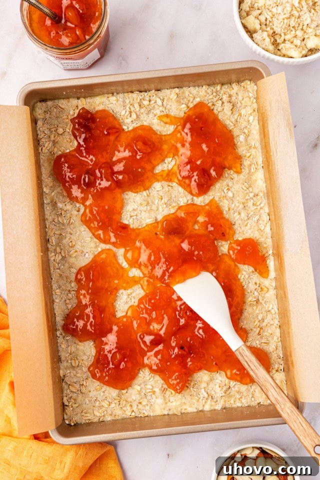 overhead view of apricot preserves being spread on top of an oat crust