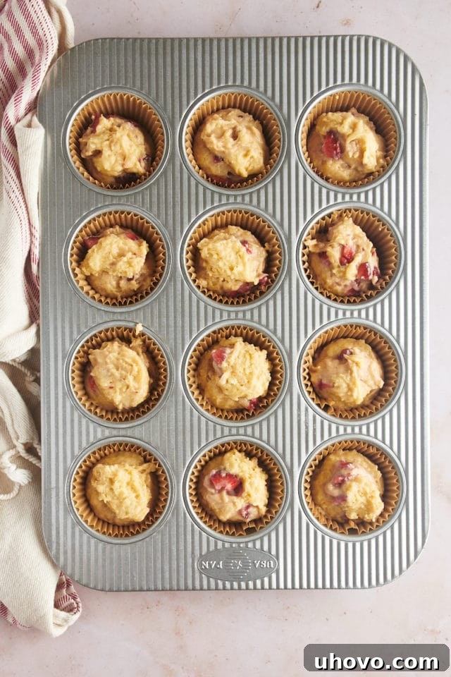 An overhead view of the muffin batter neatly portioned into each cup of a muffin pan, filling them approximately three-quarters full, ready for toppings.