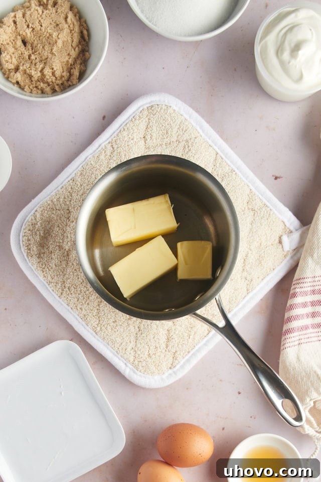 An overhead shot of butter melting and just beginning to foam in a medium saucepan over medium heat, indicating the start of the browning process.