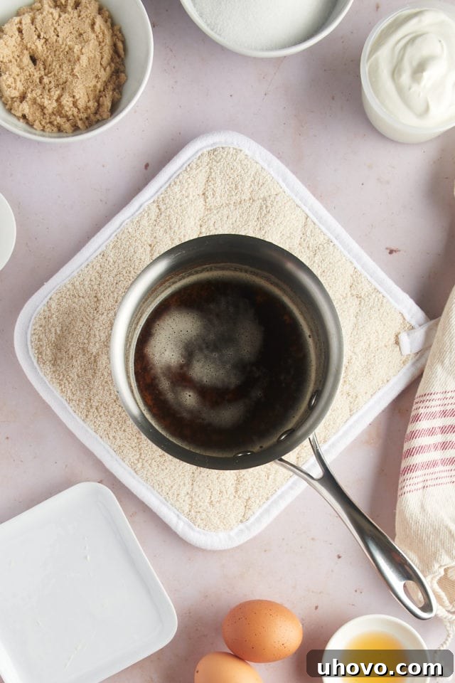 An overhead view of beautifully browned butter in a saucepan, with golden-brown specks visible at the bottom and a rich, nutty aroma developing.