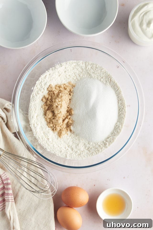 An overhead view of the combined dry ingredients for strawberry muffins—flour, baking soda, baking powder, and salt—in a glass mixing bowl, before sugars are added.