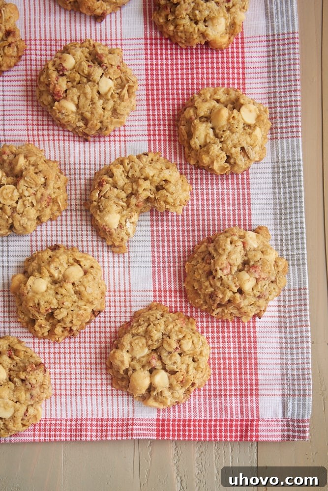 A stack of Strawberry White Chocolate Oatmeal Cookies resting gently on a white napkin, showing the beautiful speckles of strawberry and white chocolate.