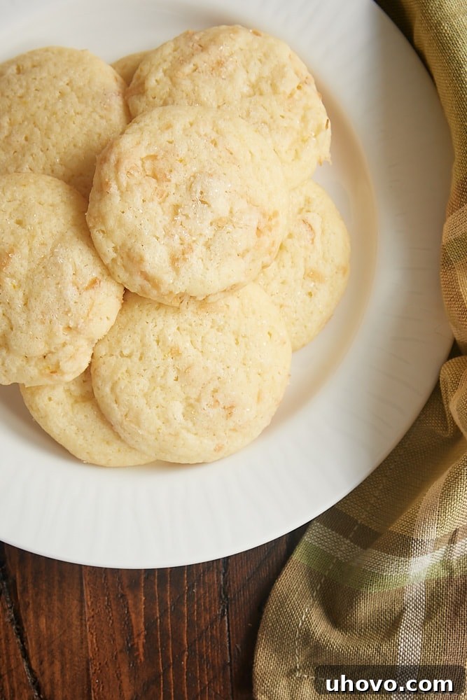 A stack of golden lemon coconut sugar cookies on a white plate, highlighting their inviting color.