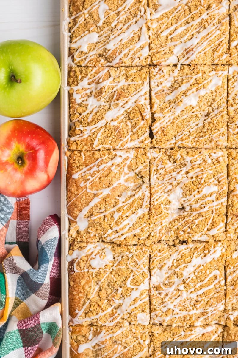 An overhead shot of the finished apple crumb sheet cake, still in its half sheet pan, beautifully drizzled with a sweet white glaze, highlighting its appealing presentation.