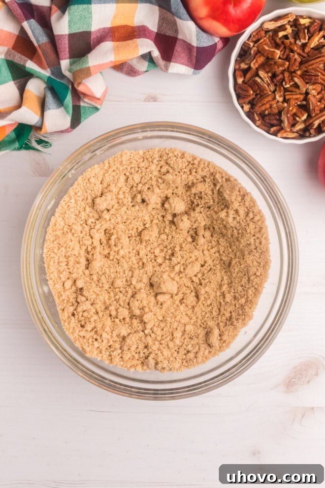 Overhead view of the crumb topping mixture in a glass mixing bowl, showcasing its perfectly crumbly texture after the butter has been cut in.