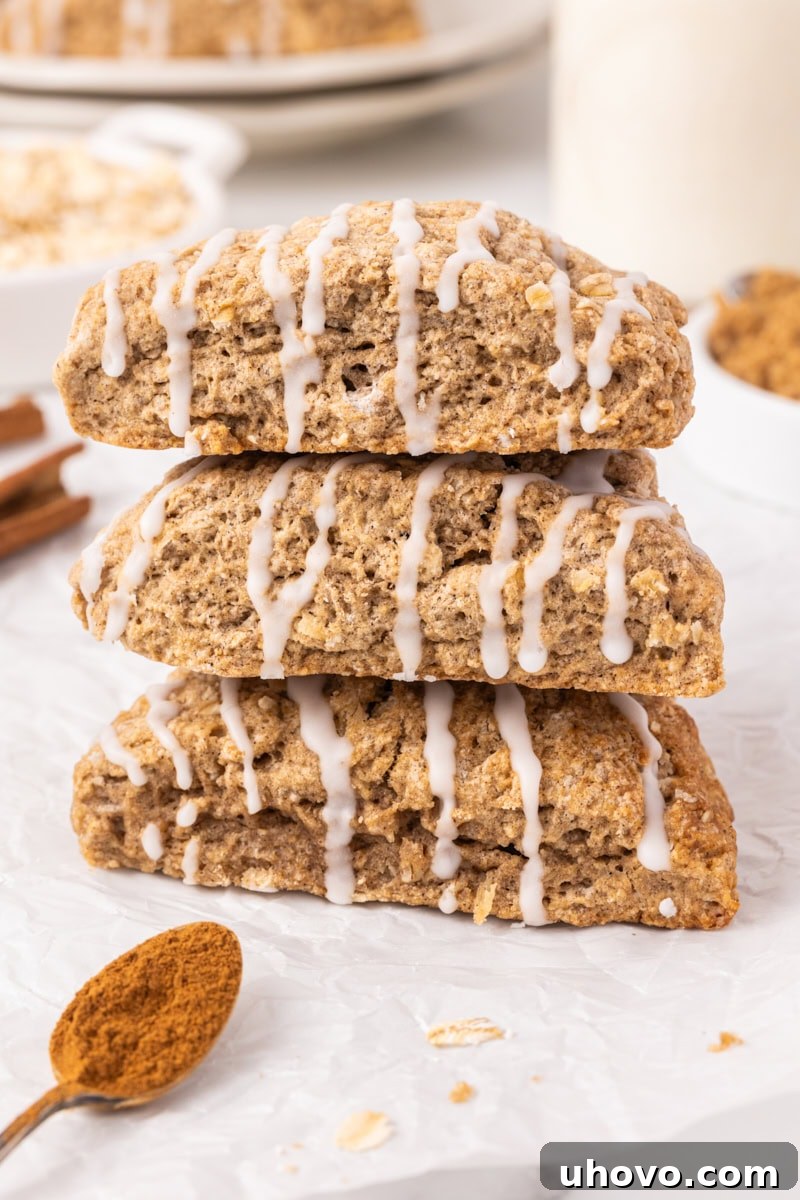 A beautifully stacked trio of cinnamon oat scones on parchment paper, showcasing their golden crust and texture.