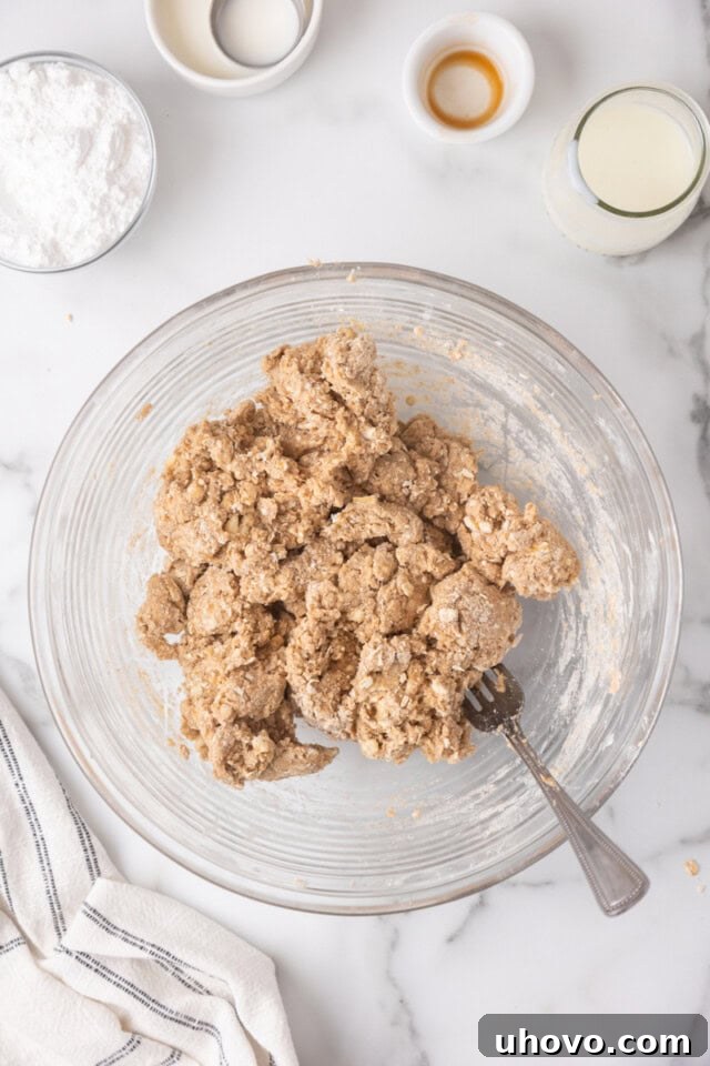 Overhead view of cinnamon oat scone dough in a glass mixing bowl, just after the wet ingredients have been incorporated.