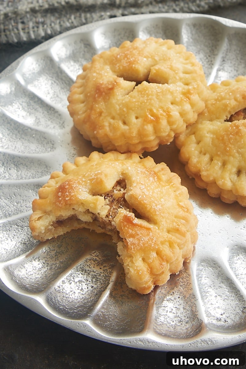 A delicious Pecan Hand Pie with a bite missing, resting on a plate with two other whole pies.