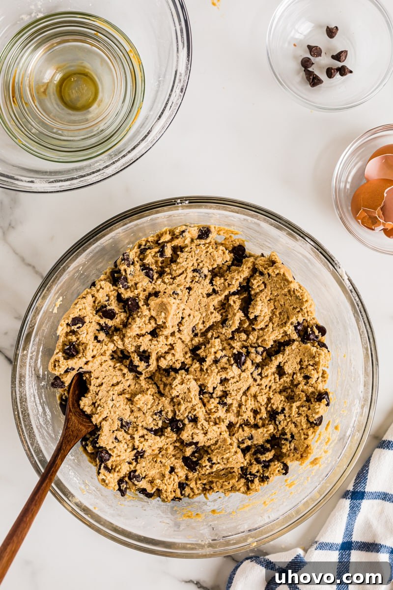 Overhead view of cookie dough in glass mixing bowl with wooden spoon