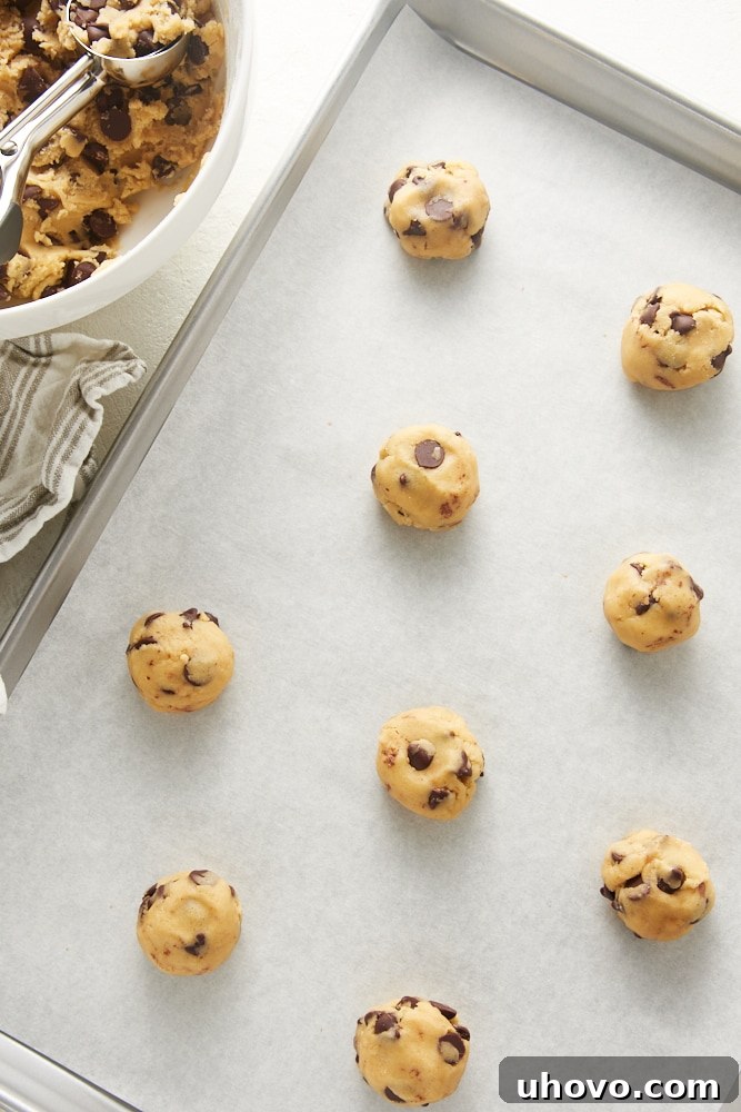 overhead view of unbaked Chewy Chocolate Chip Cookie dough on a parchment-lined baking sheet