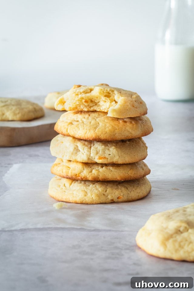 A beautiful stack of freshly baked Cream Cheese Macadamia Cookies arranged on wax paper, highlighting their tender appearance and golden-brown edges, inviting a taste.