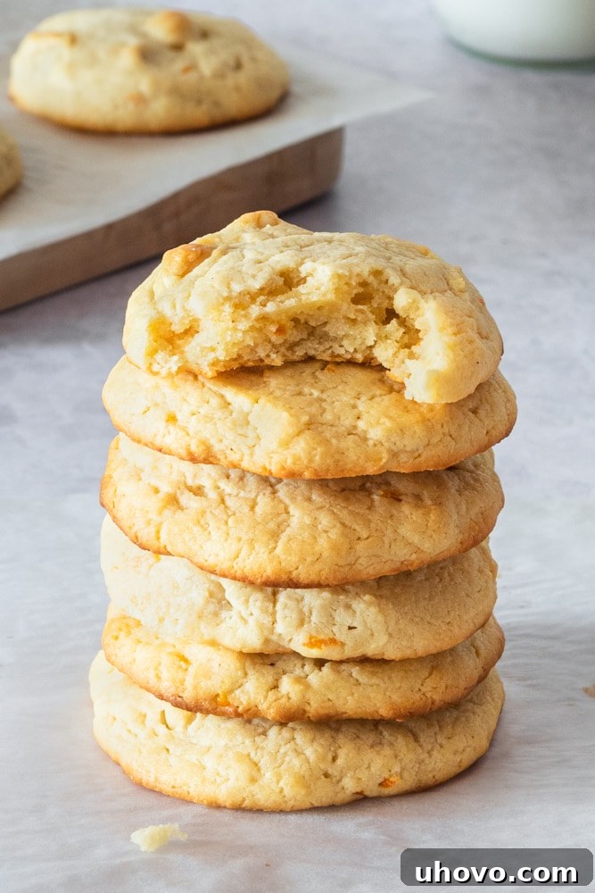 A perfectly arranged stack of golden-brown Cream Cheese Macadamia Cookies on a smooth gray surface, ready for a taste.