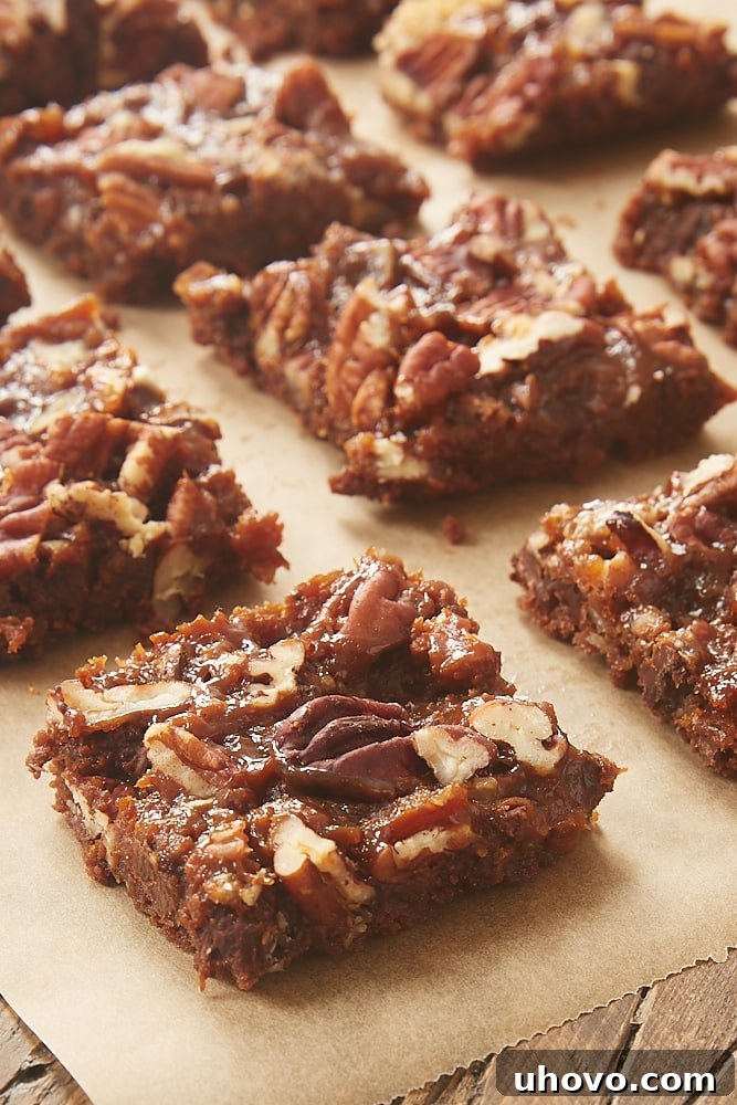 Close-up of a Dulce de Leche Magic Bar on parchment paper, showing its luscious layers of chocolate, caramel, and nuts.