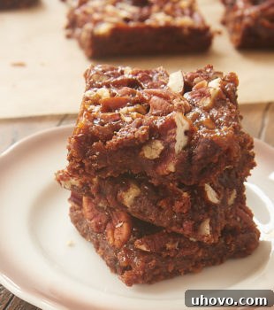A stack of golden brown Dulce de Leche Magic Bars, showing the various layers including the crumbly base, chocolate, and pecans.