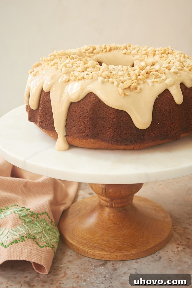 A beautifully presented Peanut Butter Bundt Cake on a stylish wooden and marble cake stand, ready to be sliced and enjoyed.