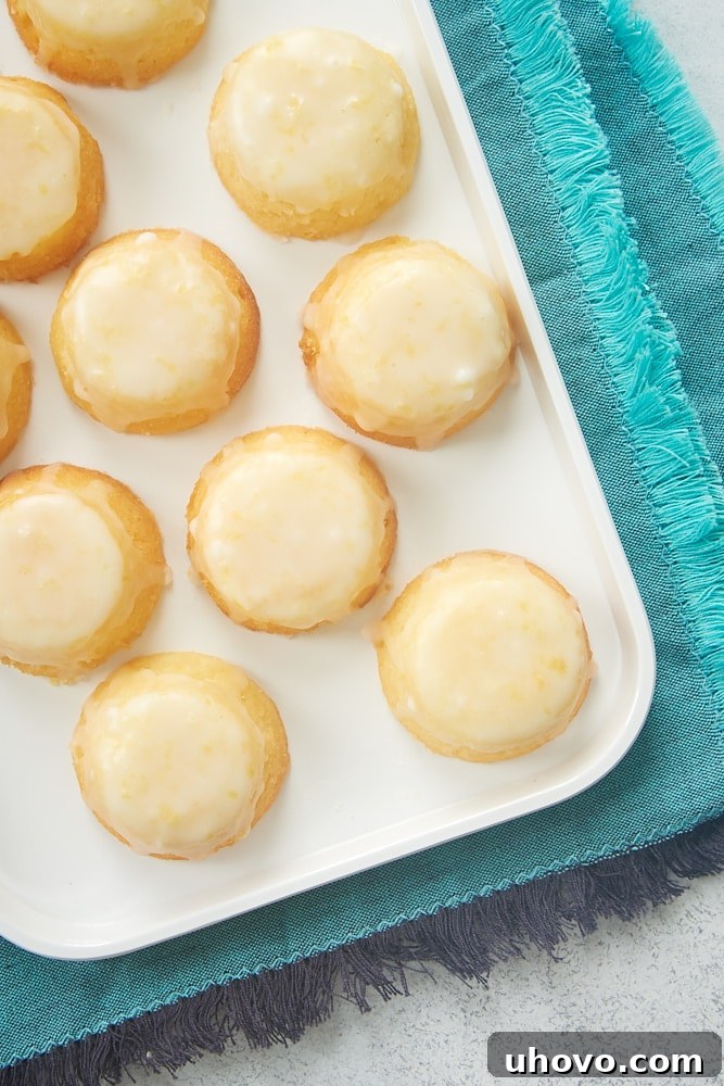 An overhead shot showcasing a beautiful arrangement of Mini Lemon Pound Cakes on a pristine white serving tray, emphasizing their small size and inviting glaze.