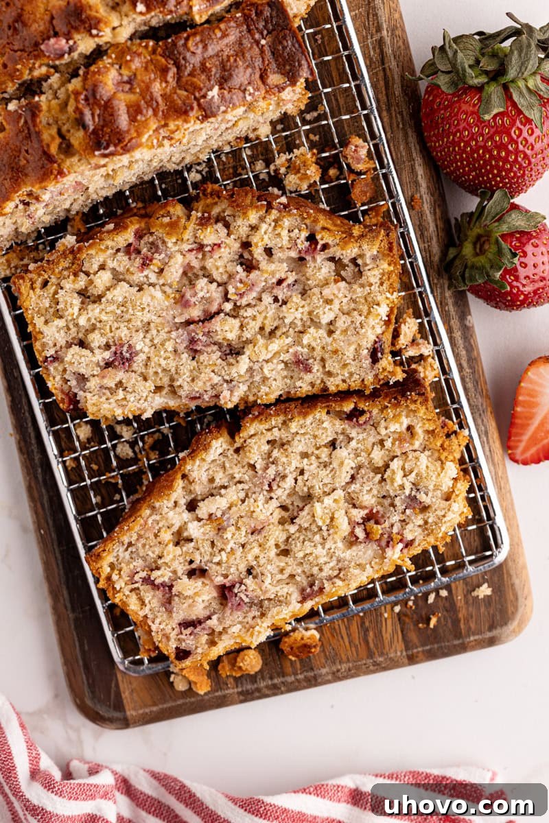 An overhead view of freshly sliced Strawberry Cream Cheese Bread on a wooden cutting board, revealing the moist texture and swirls of cream cheese throughout.