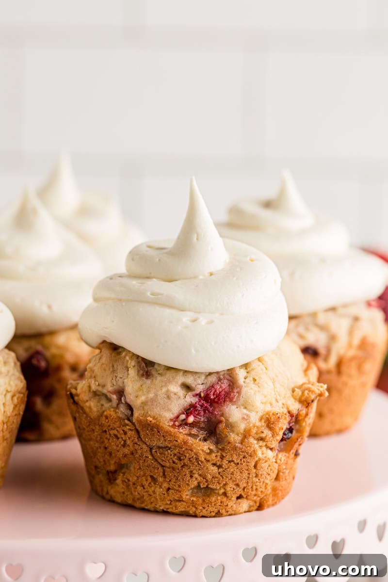 A charming display of Strawberry Cupcakes with White Chocolate Frosting arranged on a multi-tiered cake stand, ready for serving.