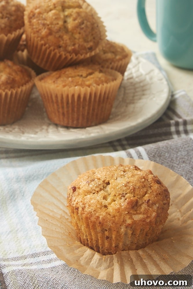 An unwrapped Brown Butter Coconut Pecan Muffin showcasing its golden-brown top and speckled texture
