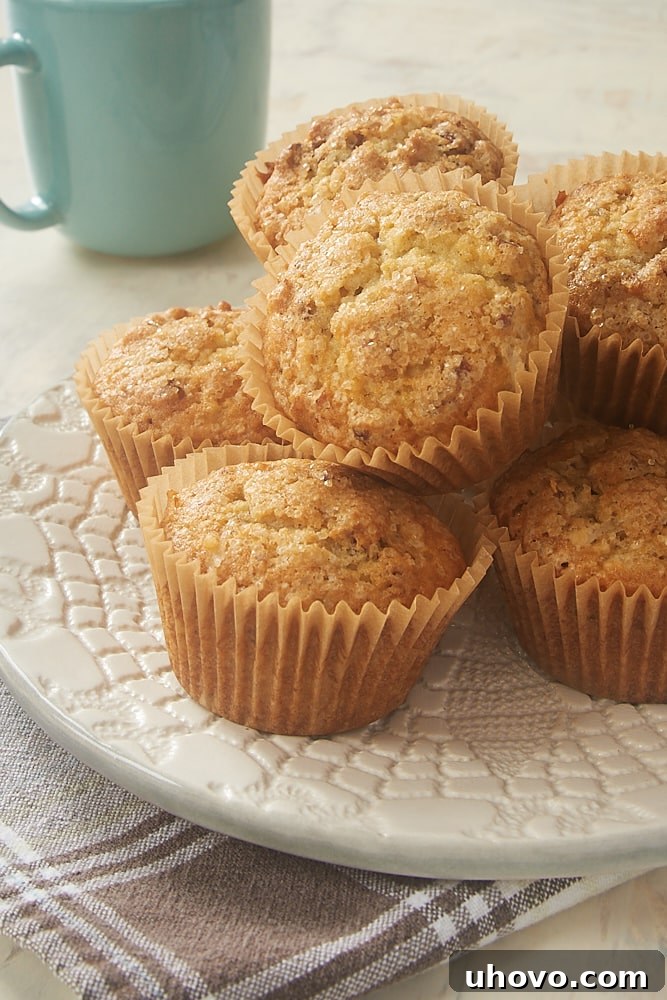 A plate stacked with freshly baked Brown Butter Coconut Pecan Muffins, showcasing their appealing golden-brown color