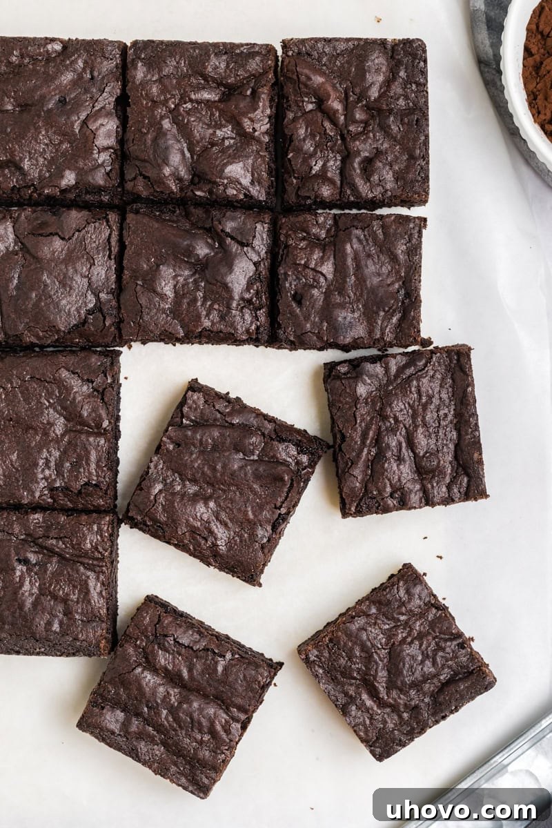 overhead view of sliced dark cocoa brownies on parchment paper