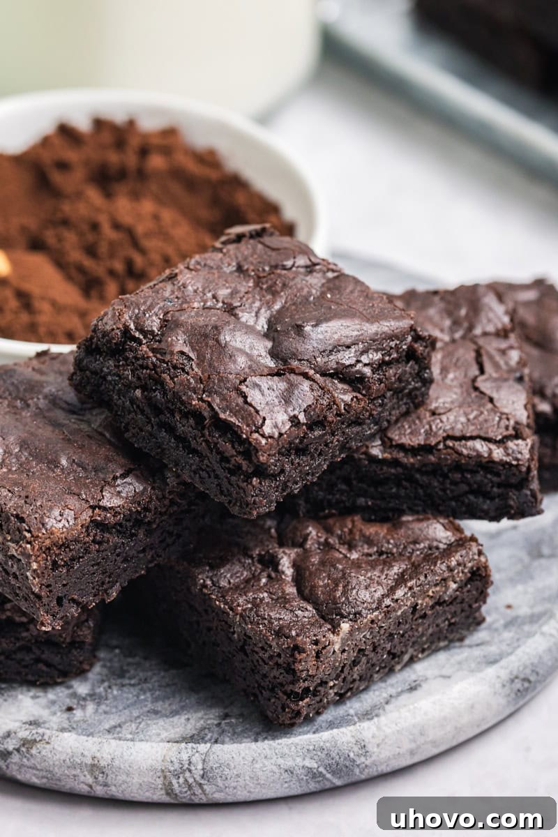 several dark cocoa brownies piled on a marble serving tray