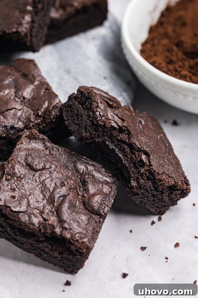 a dark cocoa brownie with a bite missing propped on more brownies