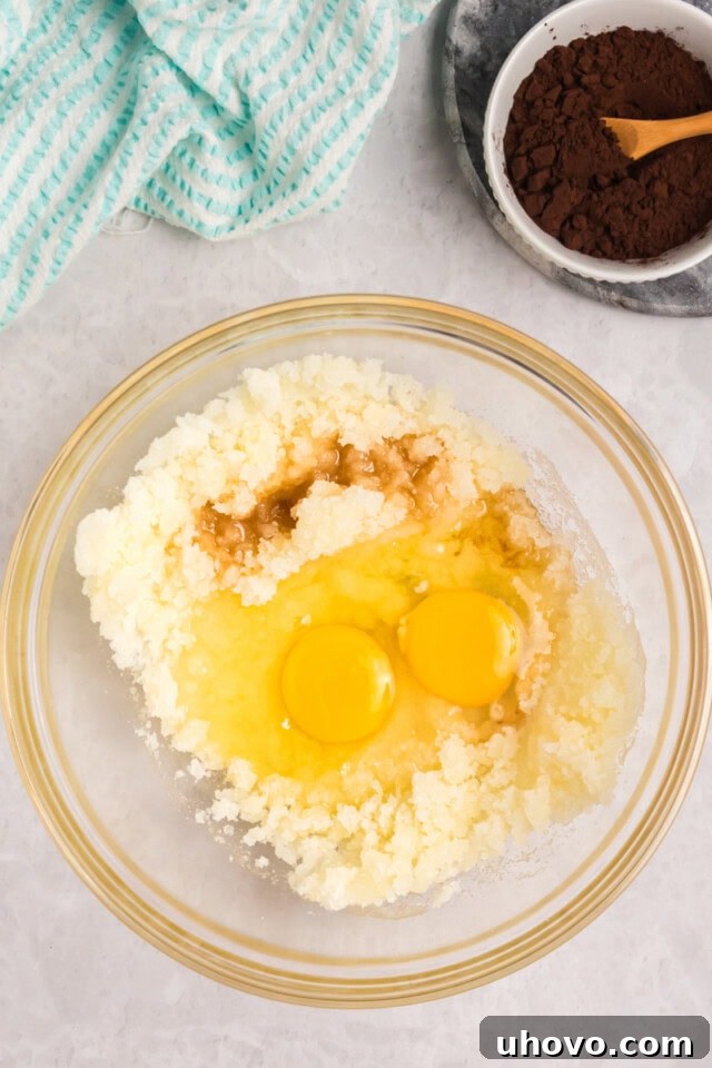 overhead view of eggs and vanilla extract added to melted butter-sugar mixture