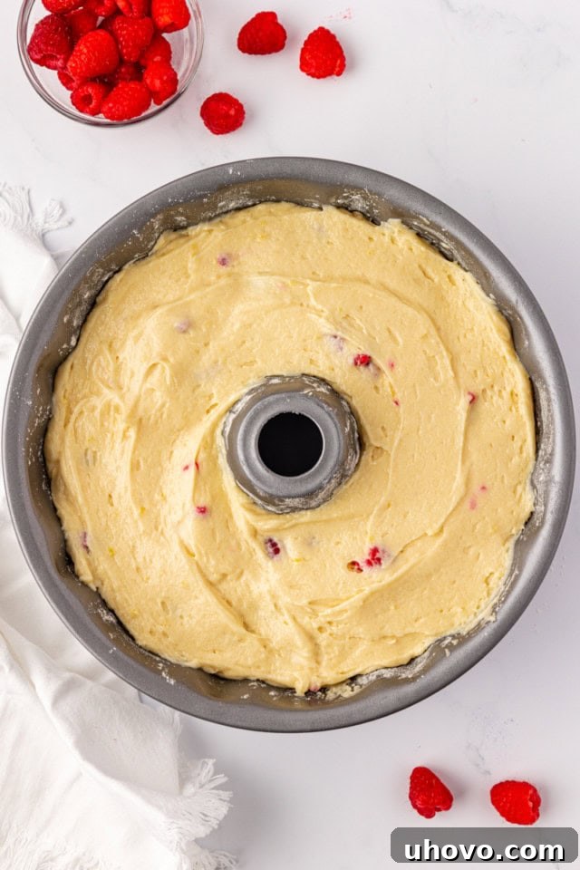 The raspberry Bundt cake batter carefully spread evenly into a prepared Bundt pan, ready for baking in the oven.