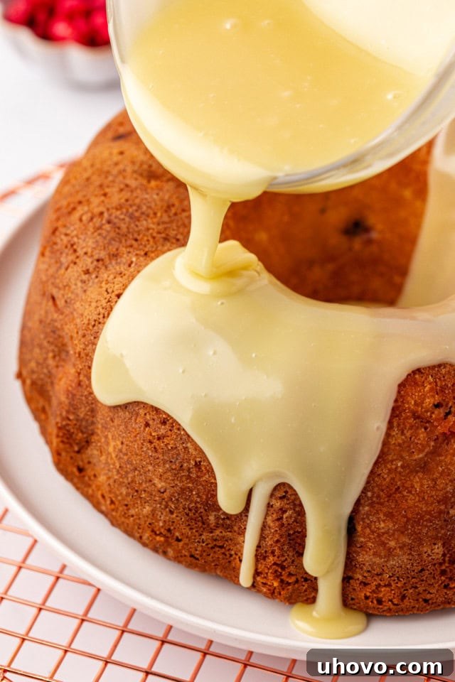 Smooth white chocolate ganache being gracefully poured over the cooled Raspberry Bundt Cake, creating a luscious cascade.