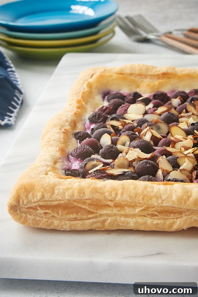 A stunning Blueberry Cream Cheese Tart displayed on a pristine marble serving board, perfect for an easy, delightful blueberry dessert made with frozen puff pastry.
