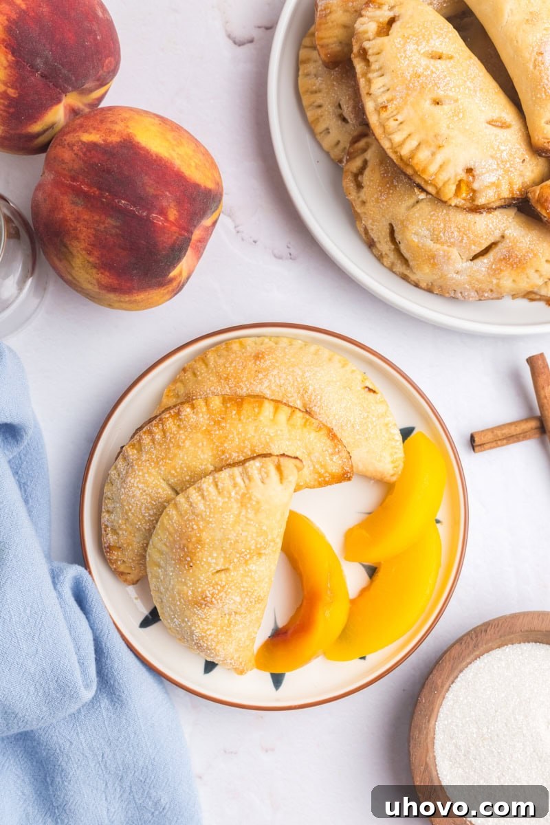overhead view of three peach hand pies and peach slices on a white plate