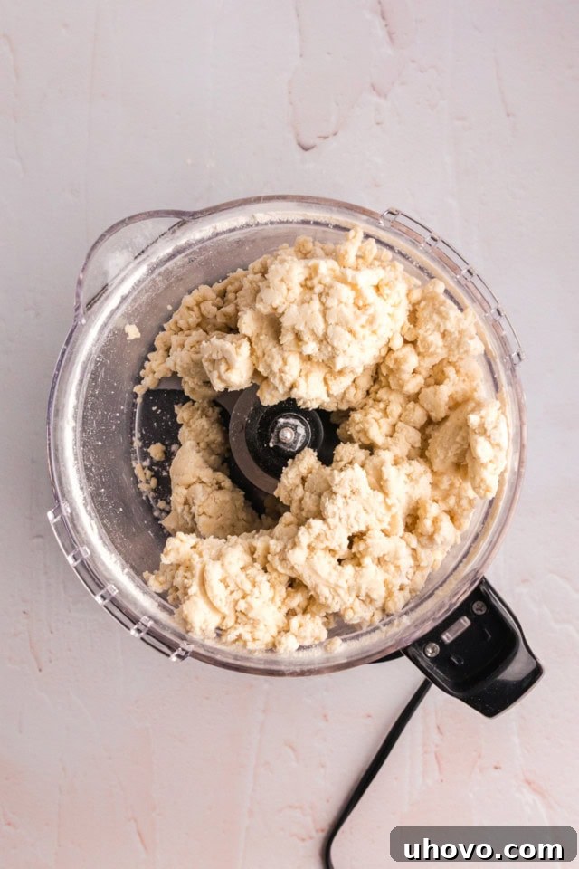 overhead view of cream cheese pastry dough in the bowl of a food processor