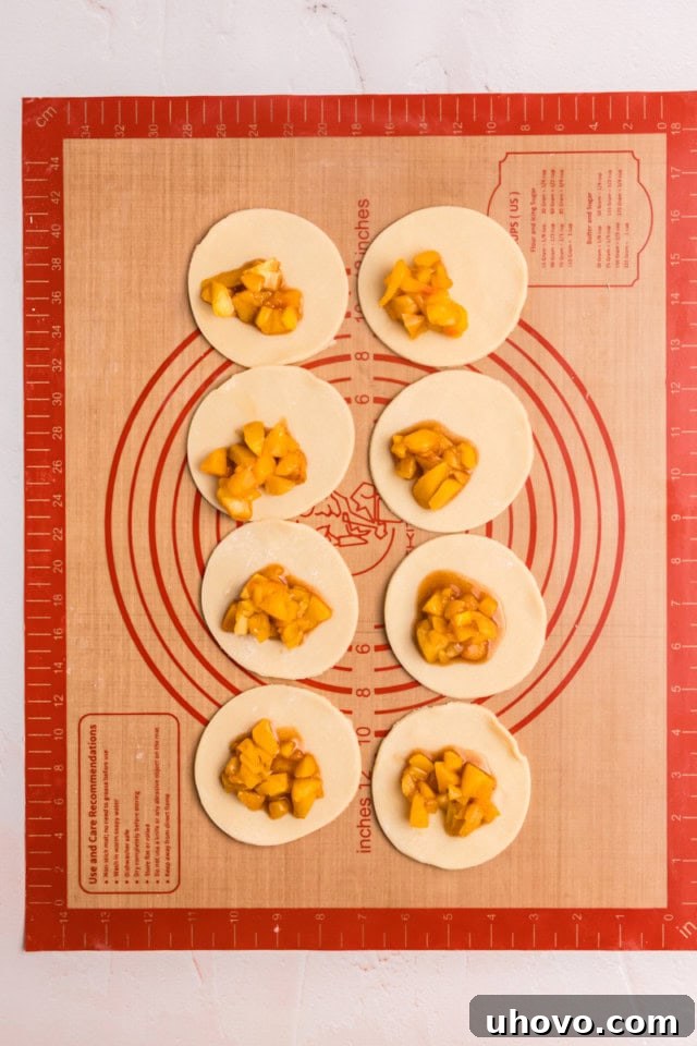 overhead view of peach hand pies being assembled on a silicone rolling mat